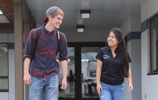 Female latina student walking with white male student